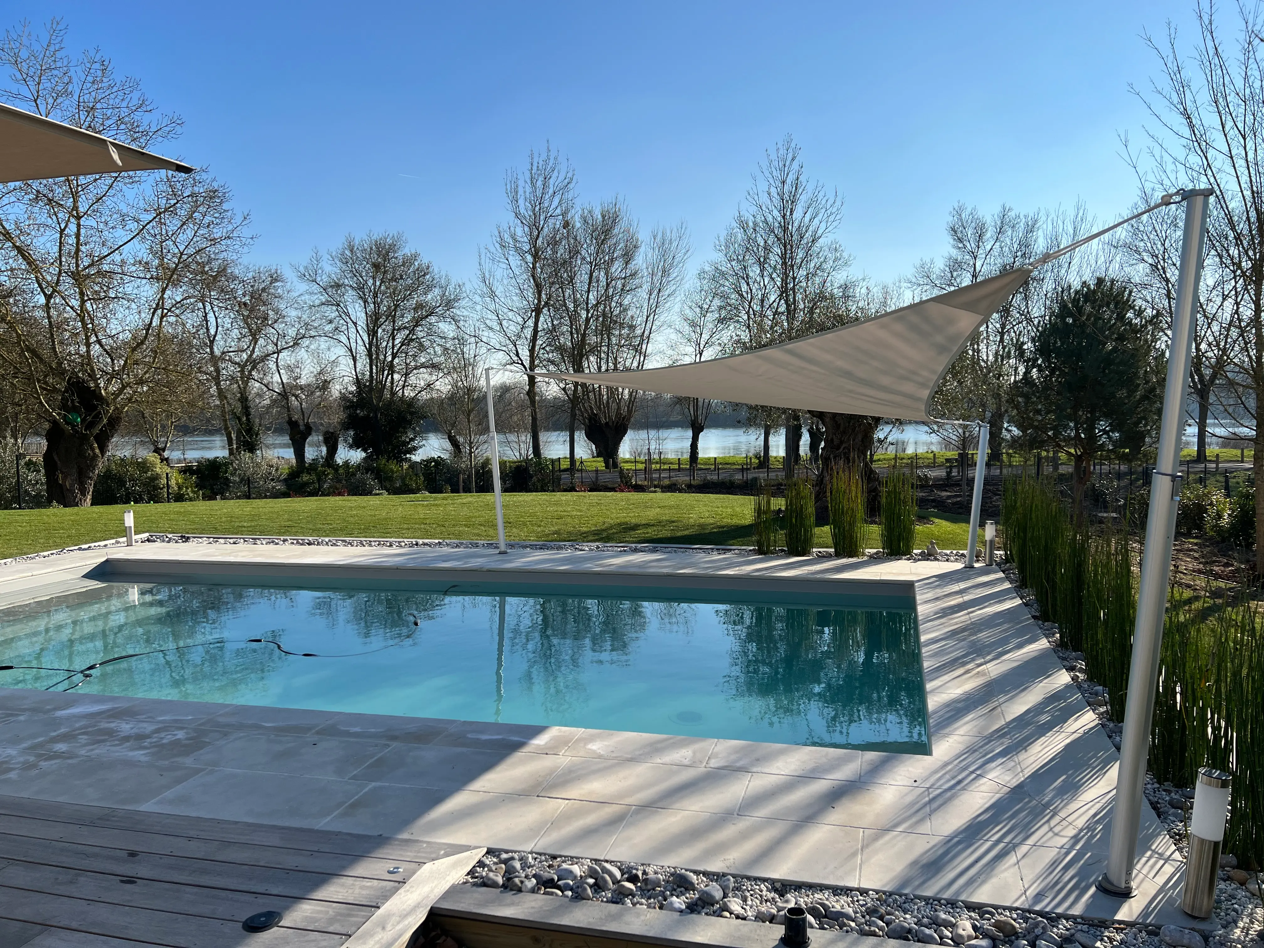 Vela de sombra triangular para crear sombra sobre una piscina con mástiles telescópicos