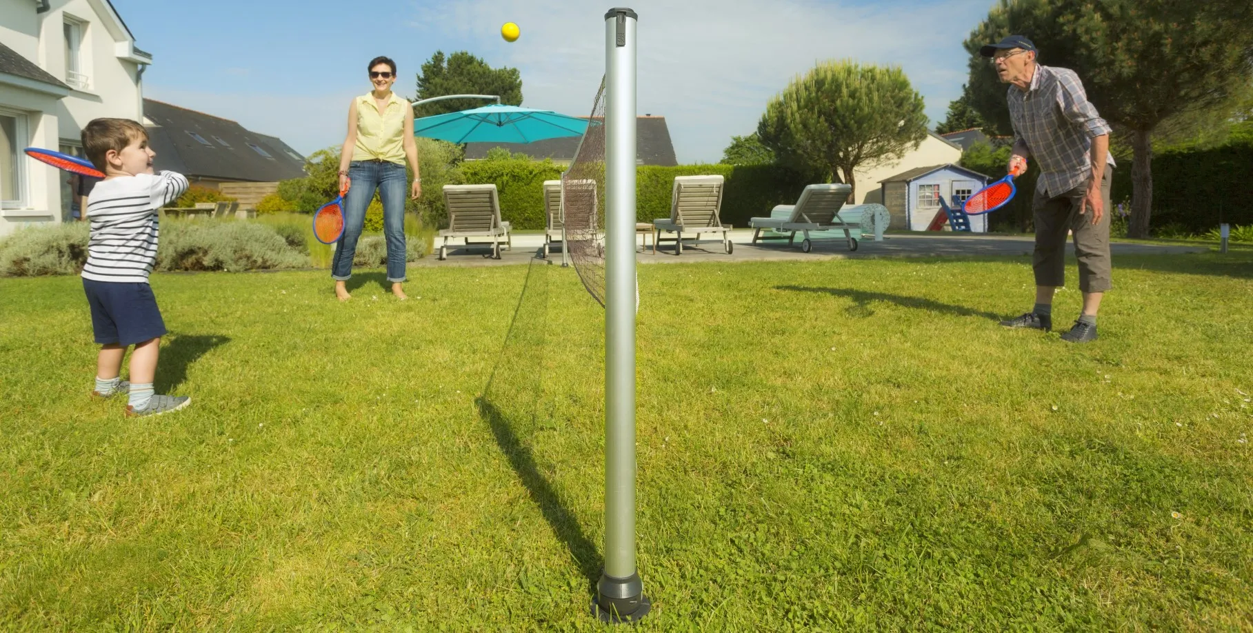 postes de tenis Gard&Rock instalados en el suelo, abuelo juega con su nieto bajo la mirada atenta de la madre