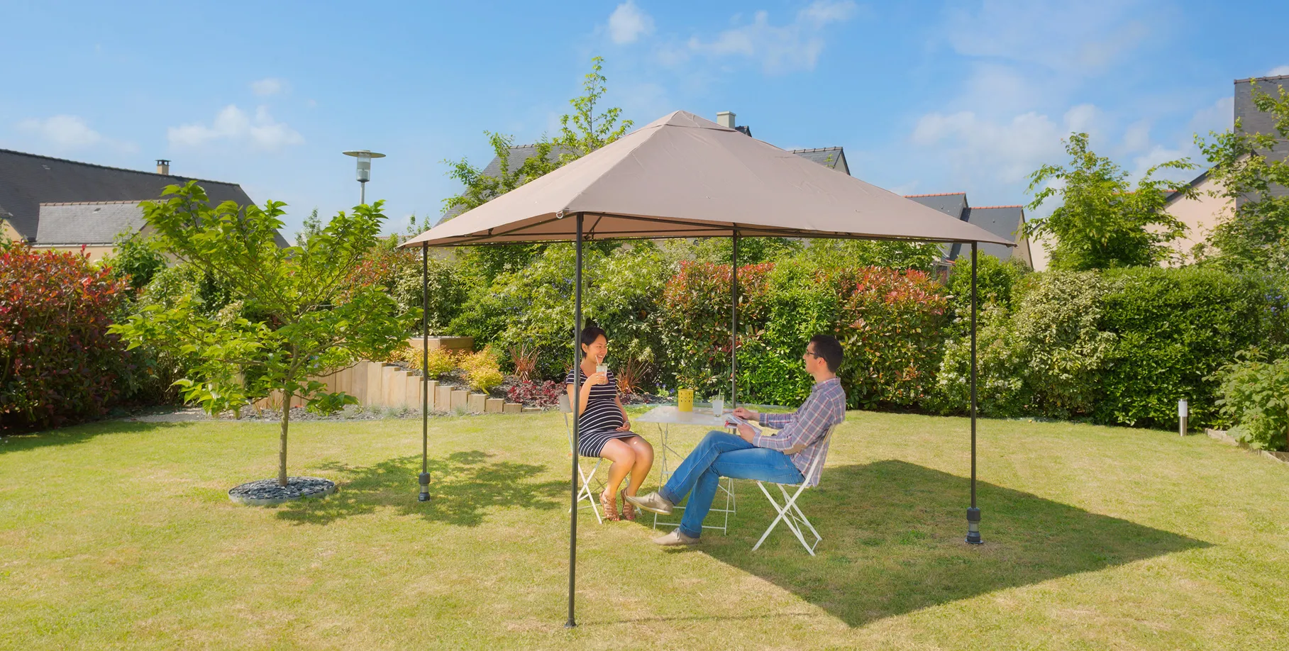 pérgola instalada con dos postes Gard&Rock encajados en bases ancladas al suelo, pareja sentada a la sombra en el jardín