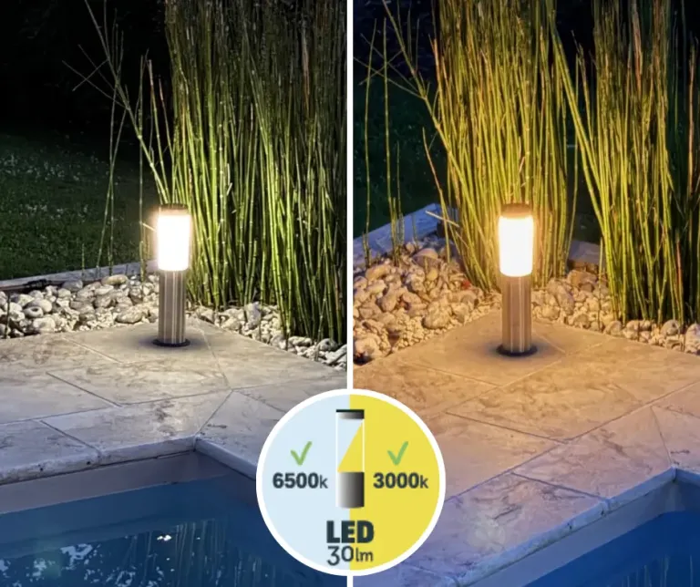 Lámpara solar discretamente integrada en un macizo vegetal cerca de una terraza de piscina de madera, luz exterior armoniosa.
