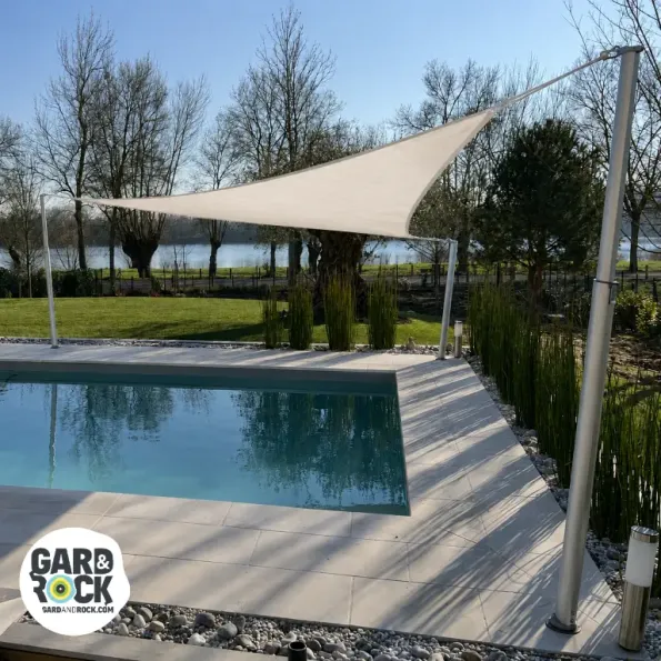 Vela de sombra tensada sobre una piscina, ofrece protección solar y una atmósfera elegante.